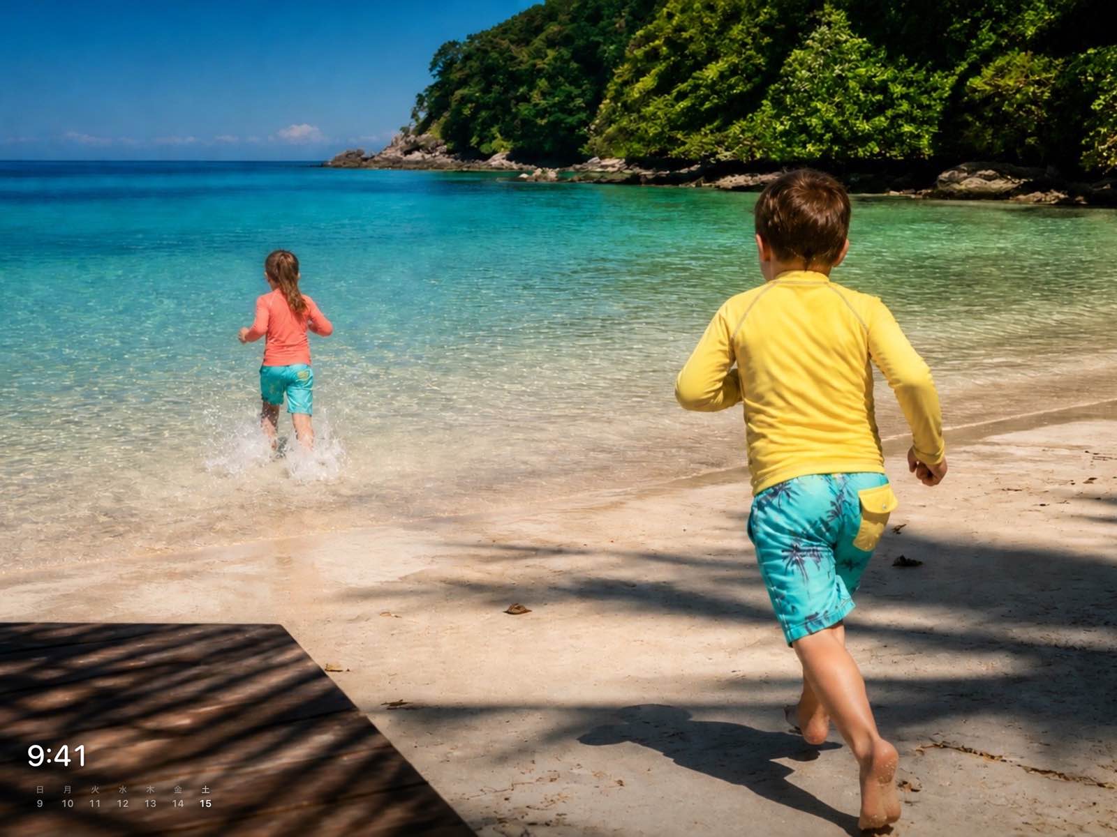 浜辺を走る子どもの写真の左下に、時刻と週間カレンダーが小さく重なっている様子。